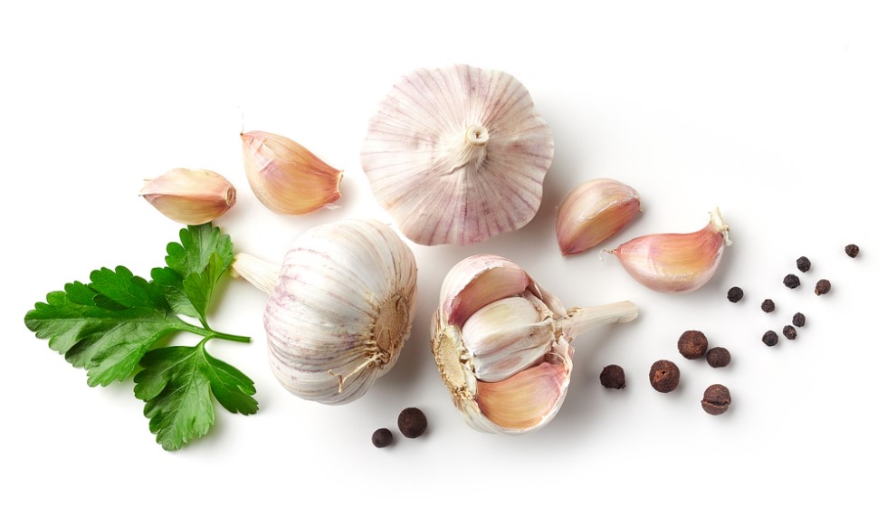 Several cloves of garlic laying beside two bulbs